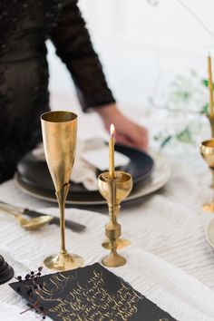 the table is set with gold candles and black plates