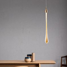 a wooden table topped with a vase next to a light hanging from a metal rod