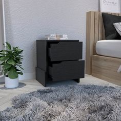 a black night stand with two drawers and a potted plant on the floor next to it