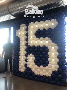 a man standing in front of a large balloon wall with the number 25 on it