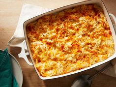 a casserole dish with cheese and meat in it on a wooden table next to two plates