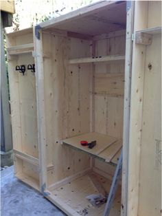 the inside of a wooden storage cabinet with tools in it's drawer and shelves