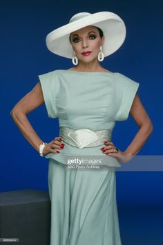 a woman in a green dress and white hat poses for the camera with her hands on her hips