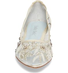 a pair of white shoes with pearls on the bottom and lace around the toes,