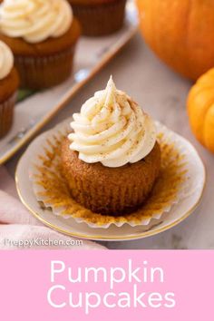 pumpkin cupcakes with cream cheese frosting on a plate next to oranges