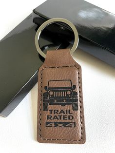 a brown leather keychain with the words trail rated on it next to a black box