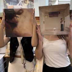 two women are holding up pictures in front of their faces