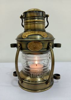 an antique brass oil lamp with the word thor on it's side and a lit candle inside