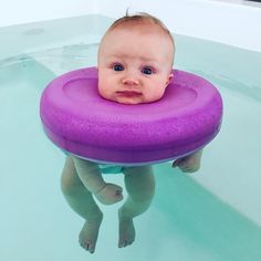 a baby is floating in the water with a purple ring around it's neck