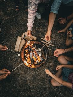 several people around a campfire with marshmallows on it