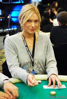 a woman sitting at a table in front of other people playing cards on the table