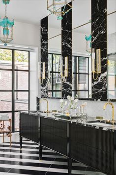 an elegant bathroom with black and white marble countertops, gold fixtures and chandeliers