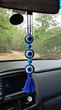 the interior of a car is decorated with blue and white crocheted beads hanging from the dash board