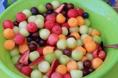 a green bowl filled with lots of fruit