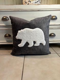 a black and white bear pillow sitting on top of a floor next to a dresser