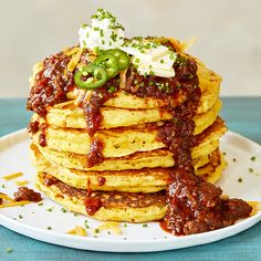 a stack of pancakes covered in sauce and toppings on top of a white plate