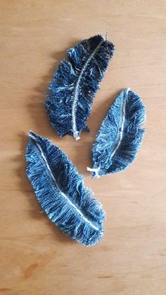 three pieces of blue feather sitting on top of a wooden table