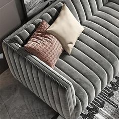 a grey couch with pillows on it in front of two pictures and a wall hanging