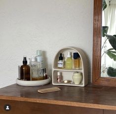 a wooden dresser topped with lots of personal care items next to a mirror and brush