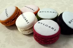 four different colored macarons with words written on them sitting next to each other