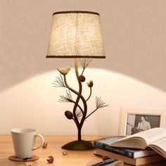 a lamp that is sitting on top of a table next to a cup and book