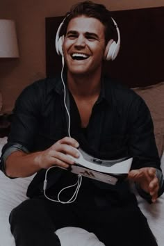 a man sitting on top of a bed wearing headphones and holding a video game controller