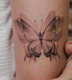 a woman's arm with a tattoo of a butterfly on the back of it