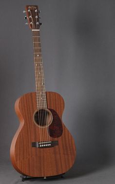 an acoustic guitar sitting on top of a stand with its strings down and the neck up