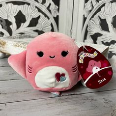 a pink stuffed animal sitting on top of a wooden table