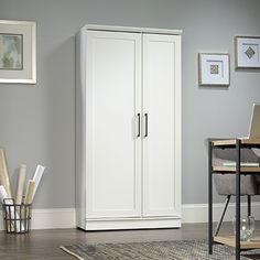 a white armoire in a living room next to a desk with a laptop on it