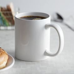 a cup of coffee next to a donut on a plate