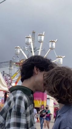 two people kissing each other in front of a carnival