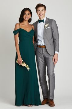 a man and woman standing next to each other in formal wear, posing for the camera