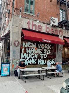 two men sitting on benches in front of the bean new york high school, much to thank you for