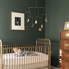 a baby in a crib next to a wall with pictures and lights on it