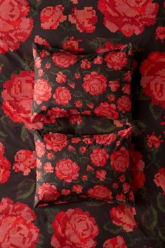 four pillows with red flowers on them sitting next to each other