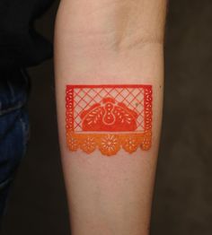 an orange and red tattoo on the arm of a person's left arm,