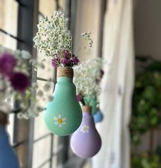 three vases with flowers hanging from them