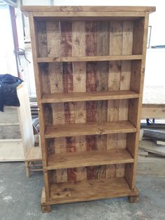 a wooden bookcase sitting on top of a floor next to a pile of wood