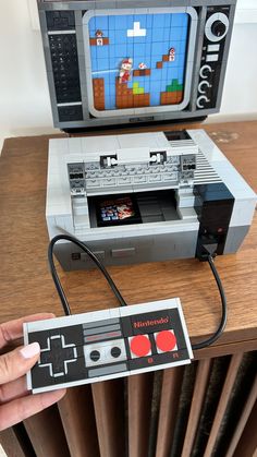 a nintendo game controller sitting on top of a wooden table next to a tv set