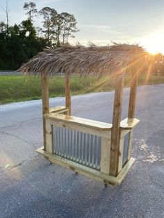 a wooden bench sitting on the side of a road next to a grass covered roof