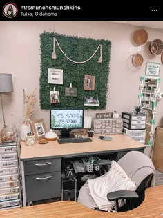 a desk with a computer on it in front of a green wall and several other items