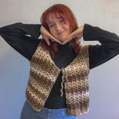 a woman with red hair wearing a crocheted vest and posing for the camera