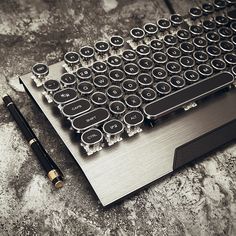 a computer keyboard sitting on top of a table next to a pen