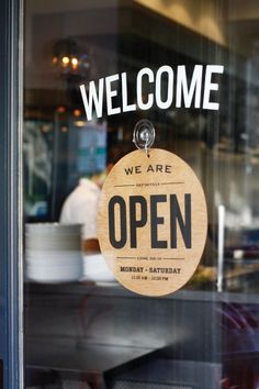 an open sign hanging in the window of a restaurant that says, we are open