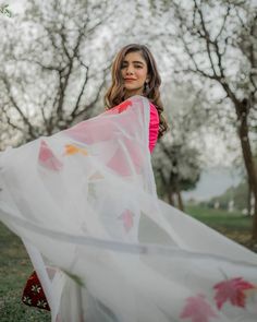 a woman standing in the grass holding a white scarf