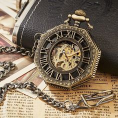 an antique pocket watch sitting on top of a table next to a chain link wallet