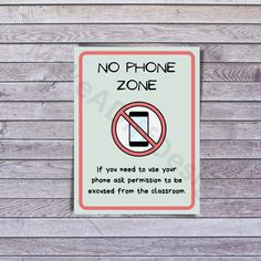 a no phone zone sign on a wooden wall