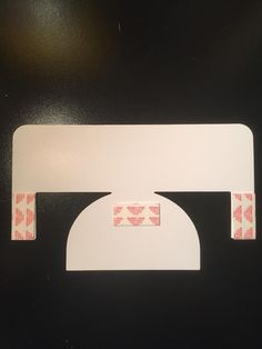 a piece of white paper with pink and red designs on it sitting on top of a black surface