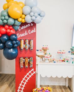 a candy stand with balloons and snacks on it